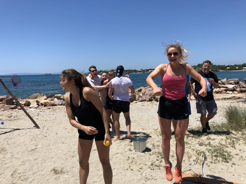 Kollegor på strand i Grekland som deltar i företagsevnet och aktiviteter